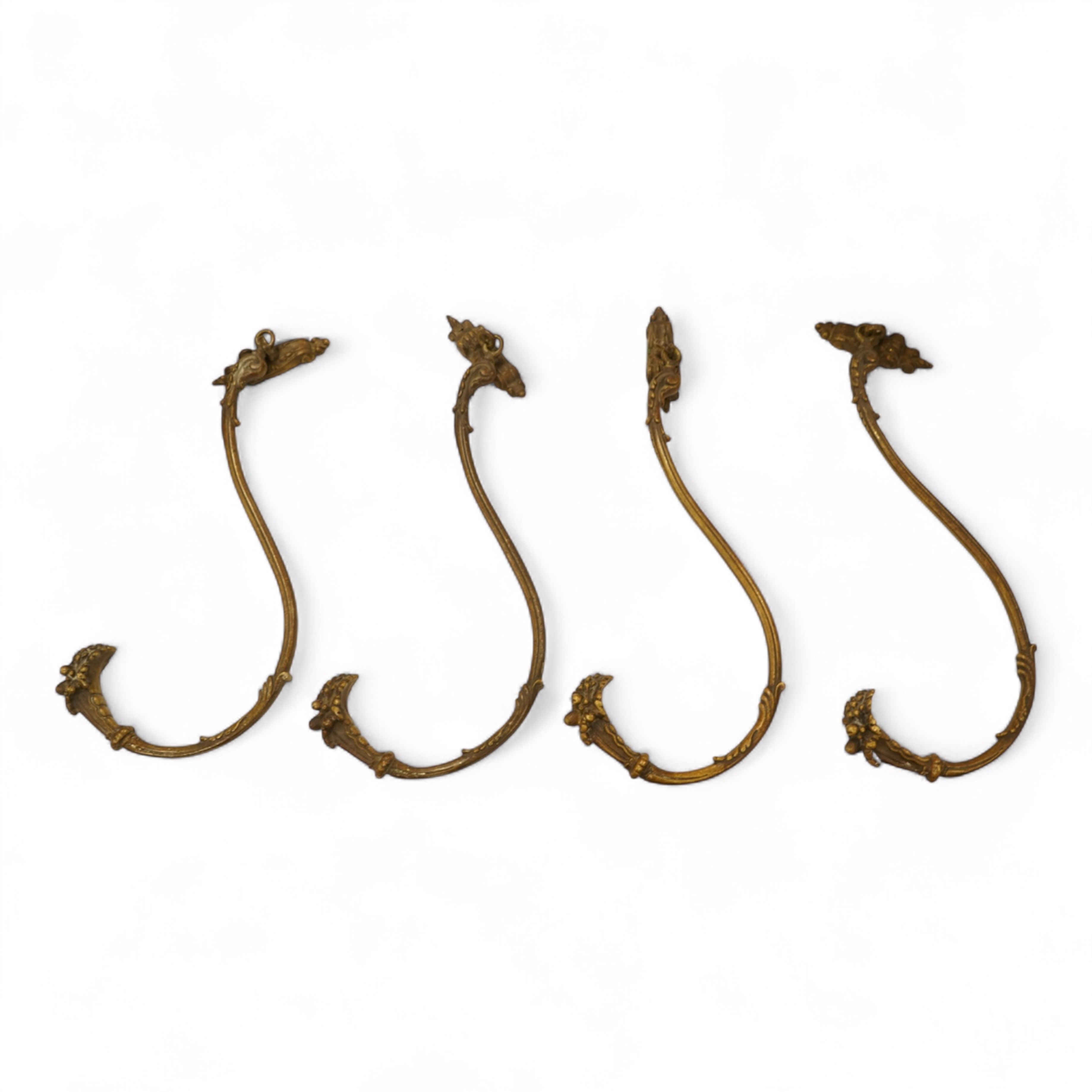 A set of four cast brass curtain tie backs, early 20th century